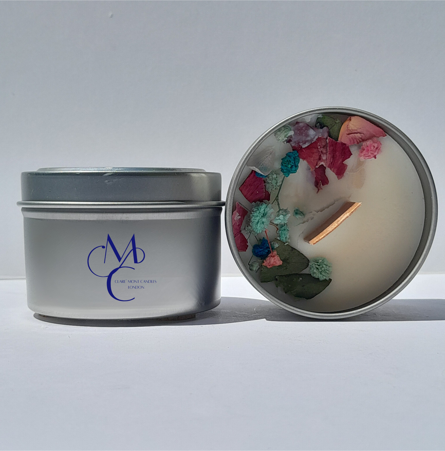 Silver candle tin with decorative candle inside on a white background