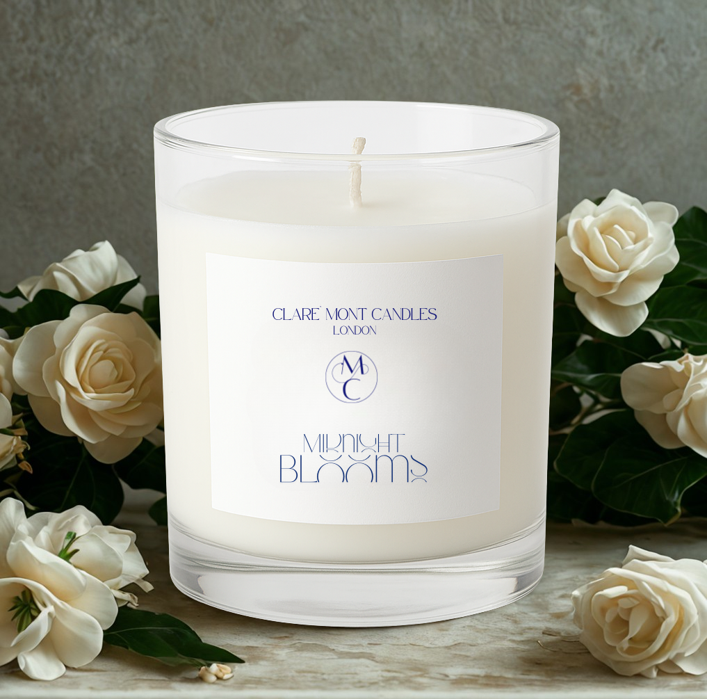 Candle with a label surrounded by white flowers on a wooden surface