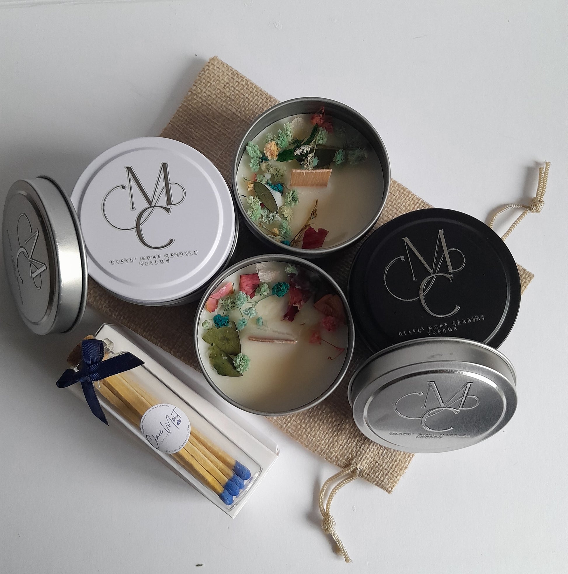 Collection of candles in tins with decorative elements on a textured surface