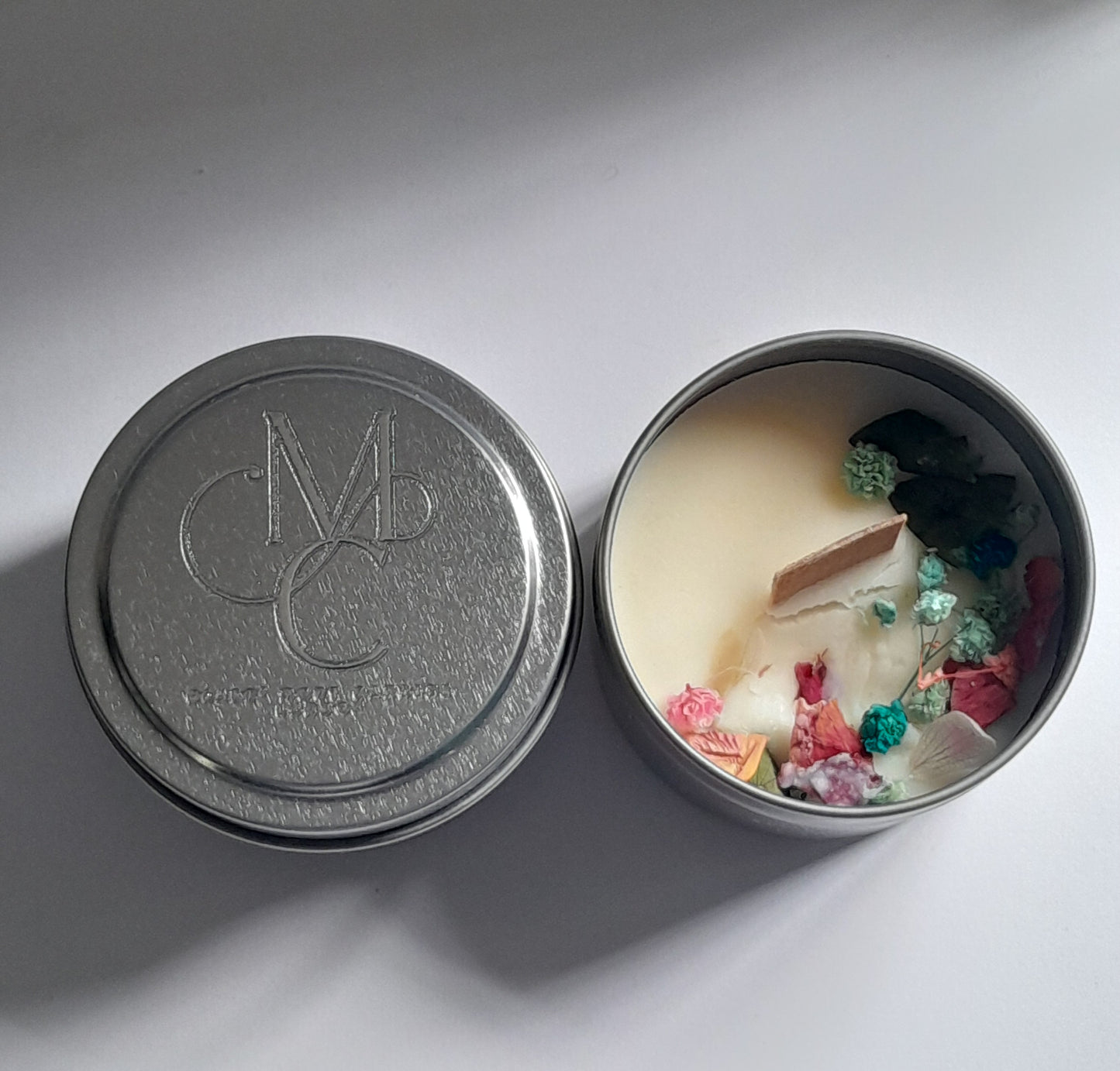 Open candle tin with decorative elements on a gray background