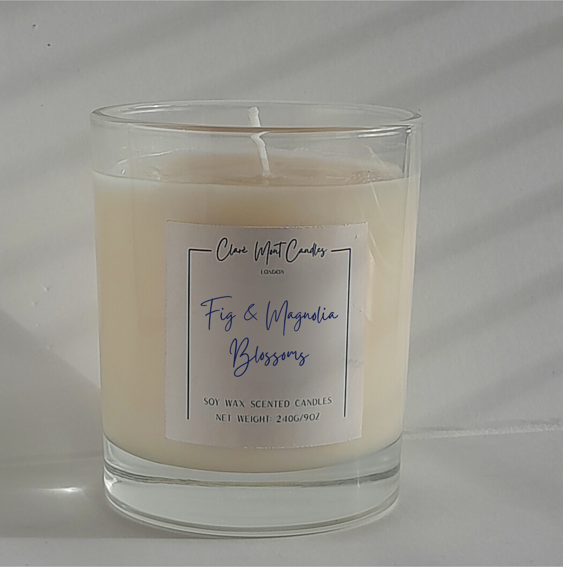 Fig & Magnolia Blossom candle in clear glass, surrounded by petals and a vintage journal