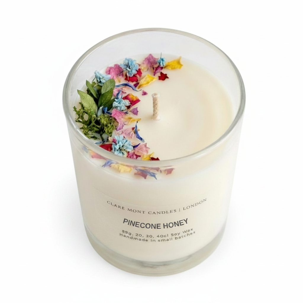 Pinecone Honey hand poured Clare' Mont Candle with colourful flowers and leaves in a glass container on a white background