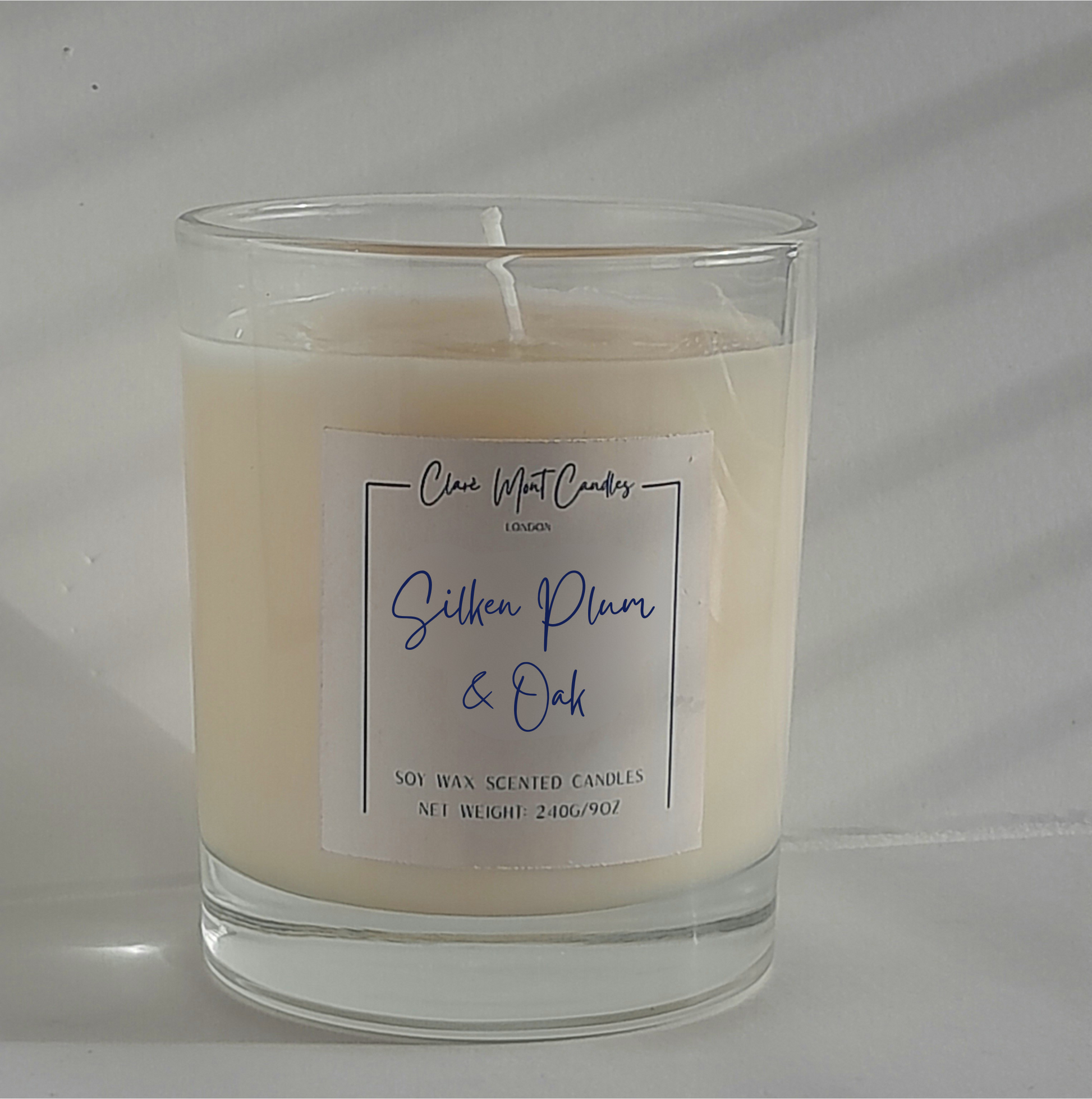 Silken Plum & Oak candle surrounded by deep-toned fabrics and dried florals in a moody, poetic setting