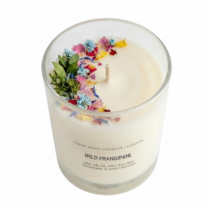 Wild Frangipani hand poured Clare' Mont Candle with floral elements in a glass jar on a white background