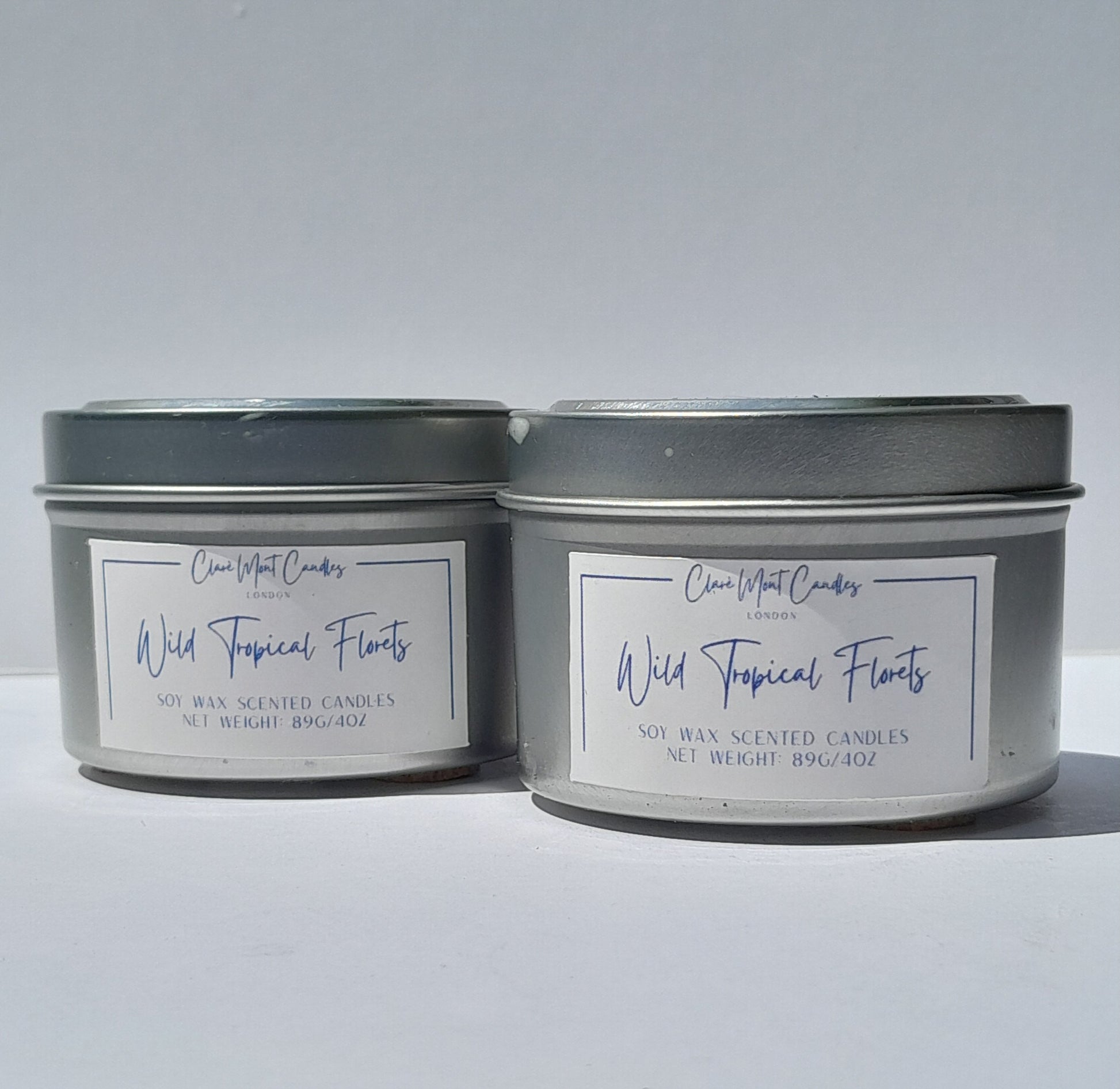 Two tins of 'Wild Tropical Florals' candles  side by side with labels on a white background