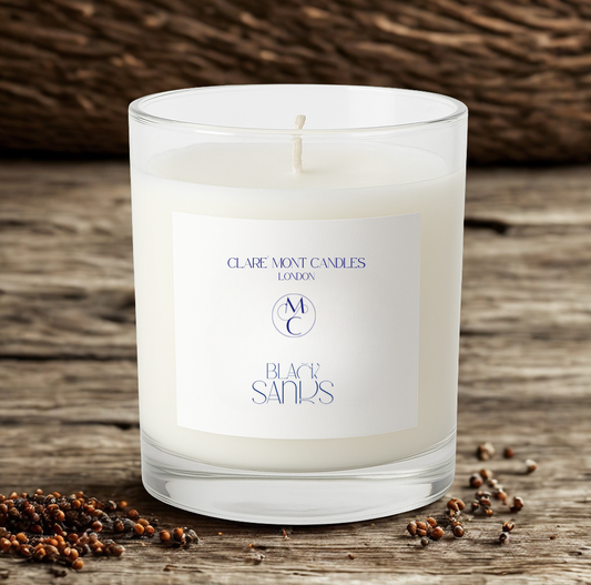 White candle with a label on a wooden surface with black sandalwood.