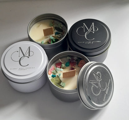 Four tins with decorative candles inside, featuring a brand logo on the lids.