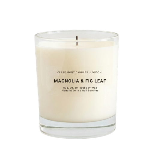 Candle with 'Magnolia & Fig Leaf' scent in a clear glass container on a white background