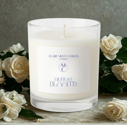 Candle with a label surrounded by white flowers on a wooden surface