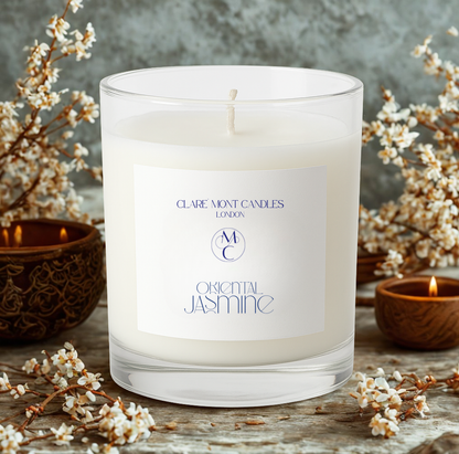 Candle with 'Claremont Candles London' label surrounded by floral branches on a wooden surface.