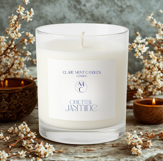 Candle with 'Claremont Candles London' label surrounded by floral branches on a wooden surface.