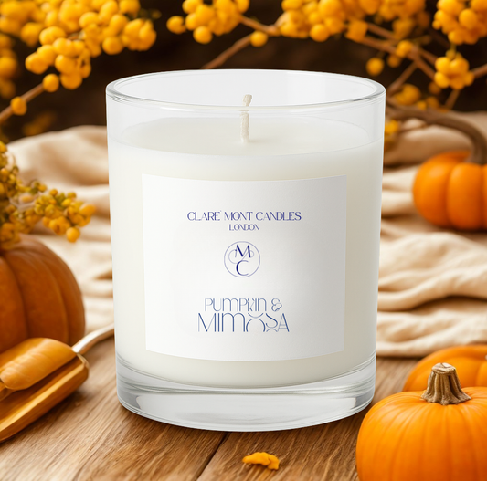 Candle with a label in a festive setting with pumpkins and yellow flowers